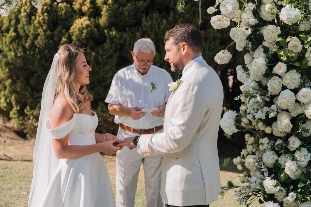 A sunlit garden wedding ceremony with white floral arrangements and elegant decor.