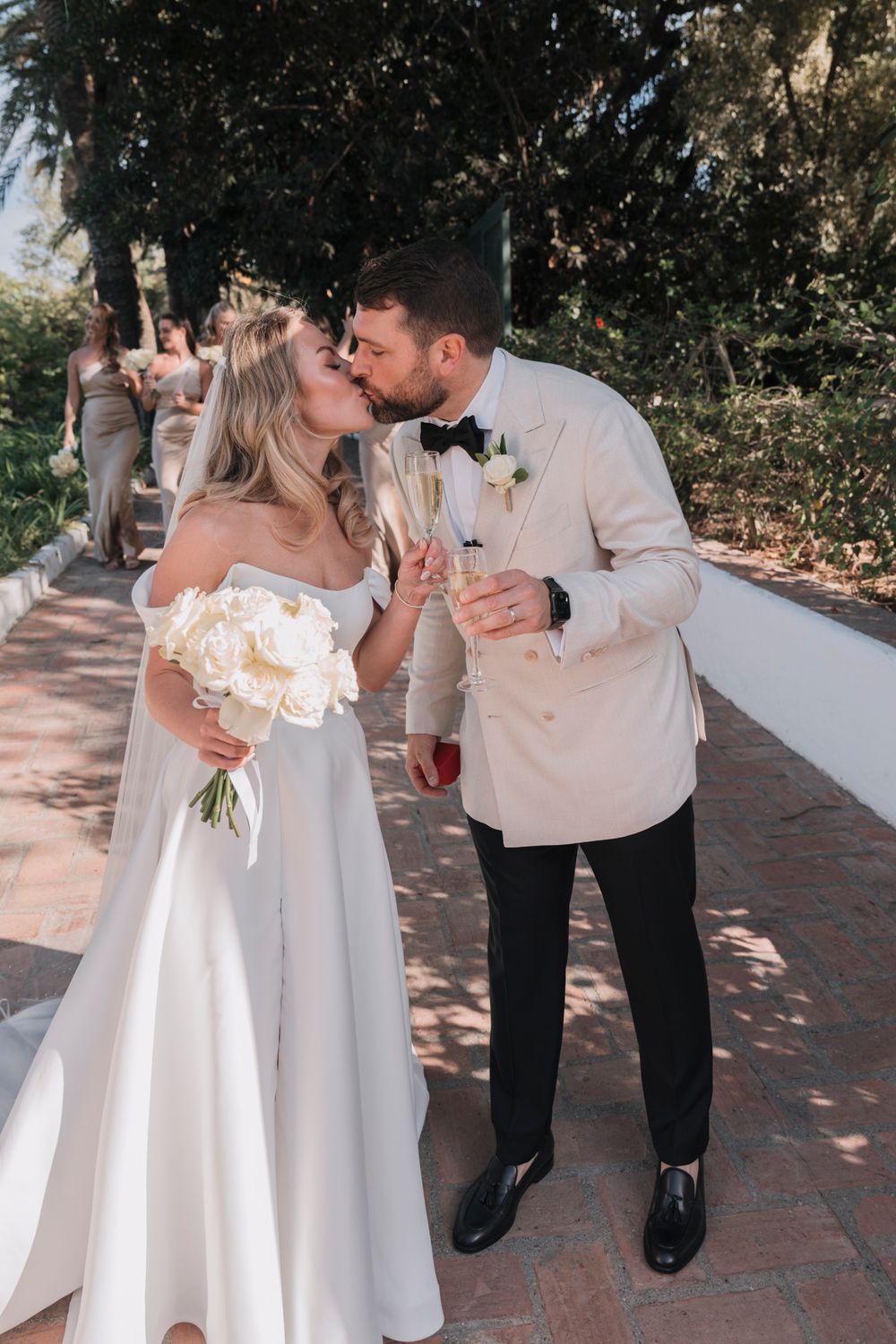 Romantic moment between newlyweds on a palm-lined brick pathway.
