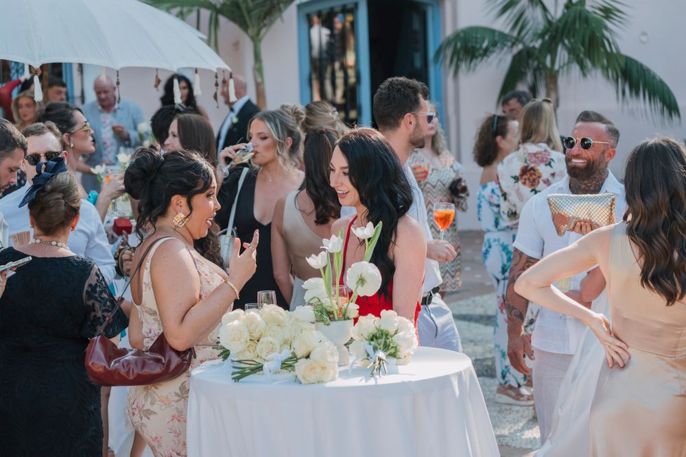 Wedding reception guests gathering around cocktail tables at an elegant outdoor venue.