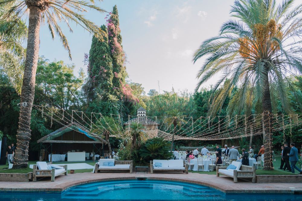 Luxury pool area with string lights and palm trees at a Mediterranean resort.