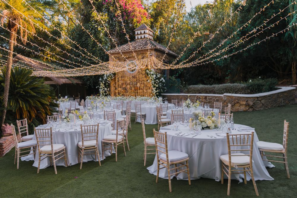 Elegant outdoor wedding reception setup with string lights and white table settings.