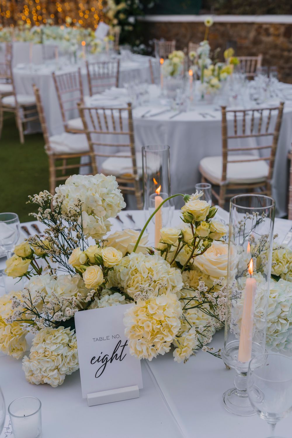 Wedding table setting with table number eight card and white and yellow floral centerpiece.