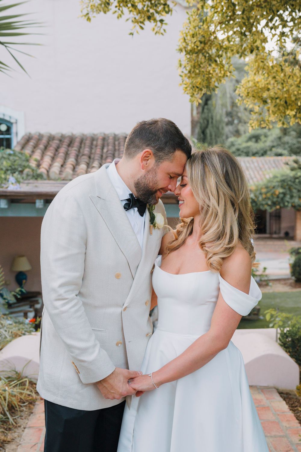 A romantic wedding portrait of a couple sharing an intimate moment in a garden setting.