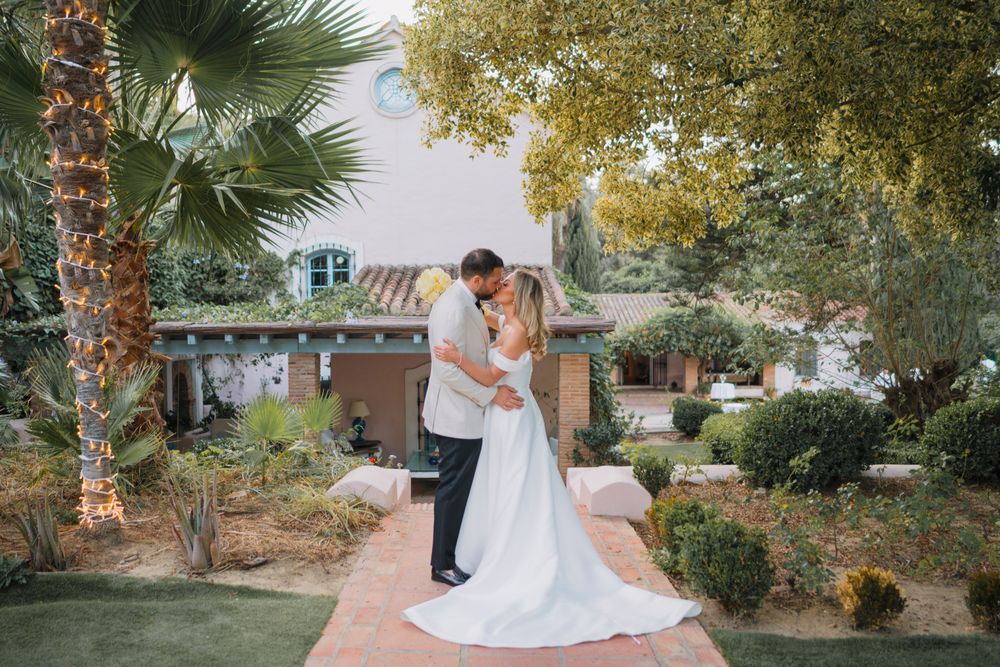 A romantic wedding portrait with the couple embracing on a brick path surrounded by tropical landscaping.