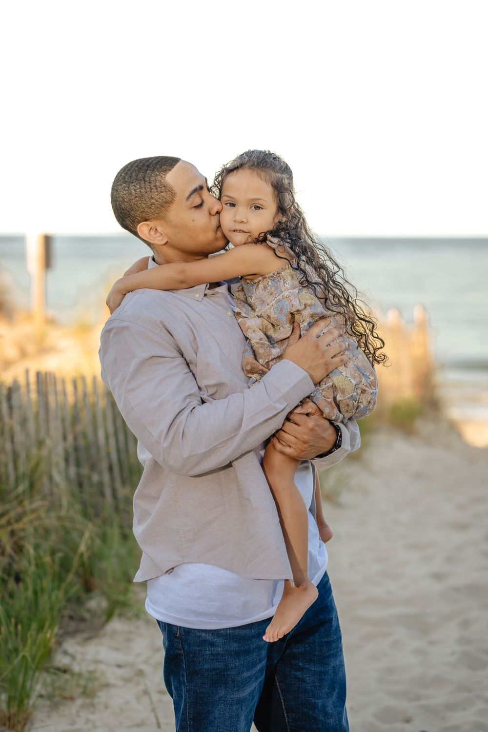 A tender moment captured between parent and child on a beach at sunset.