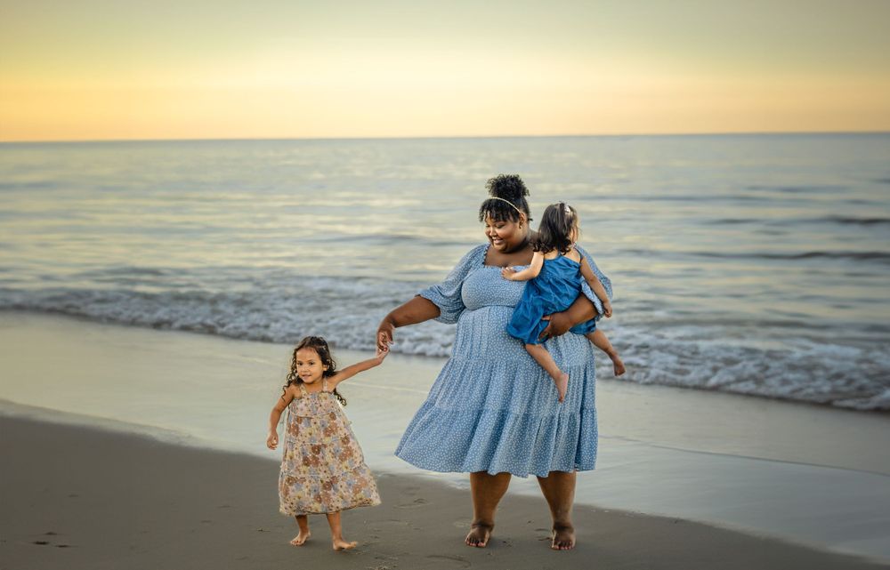 Family hands and dance together on the beach at sunset.