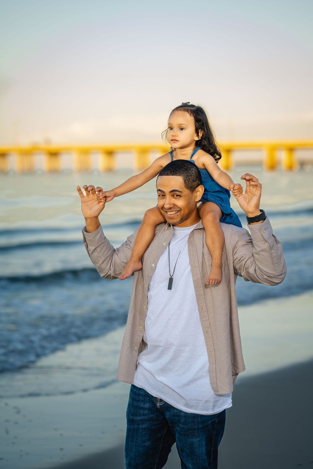 A joyful moment between parent and child playing on shoulders at the beach.