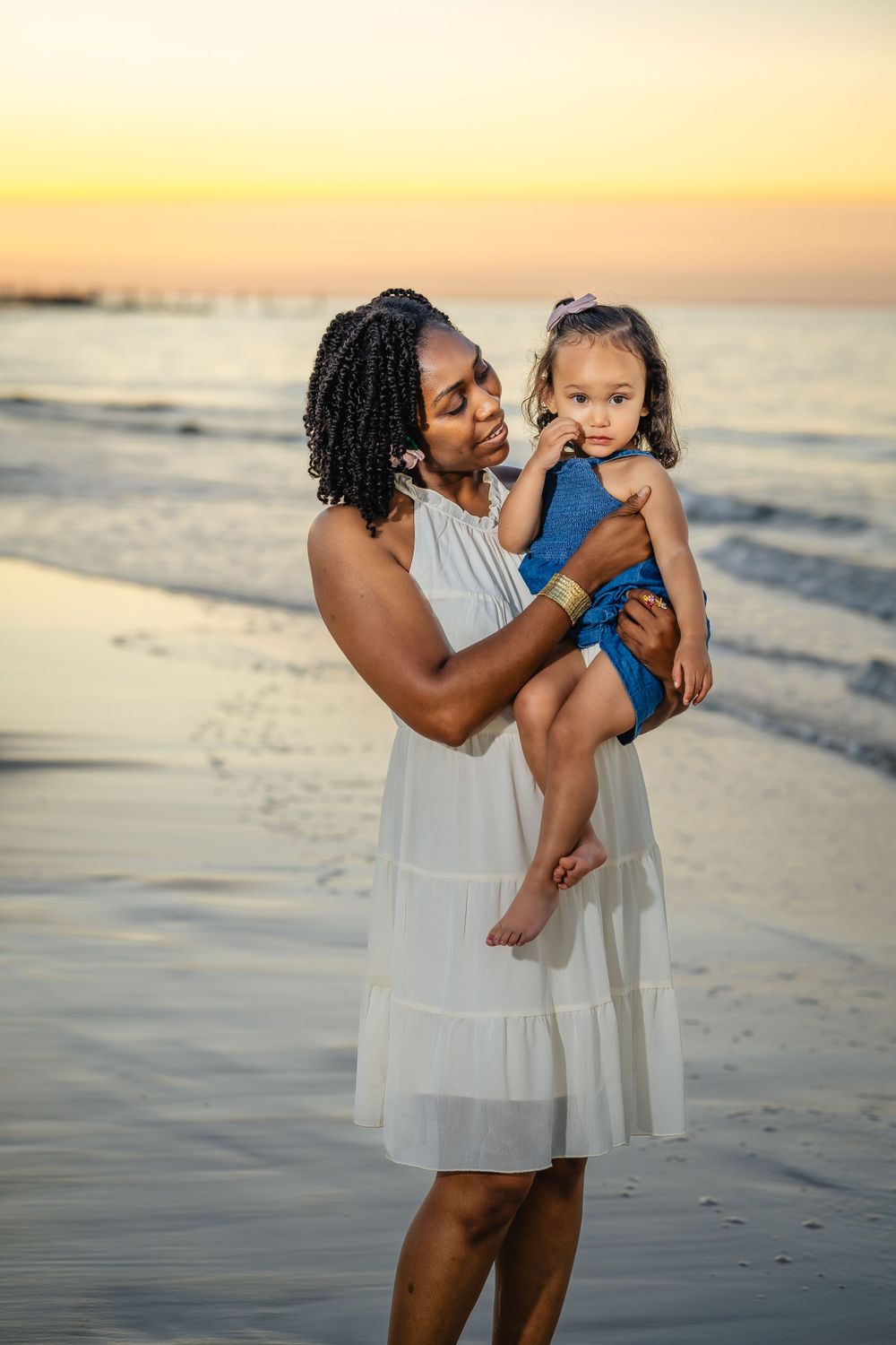 A tender moment between parent and child on a sunset beach.