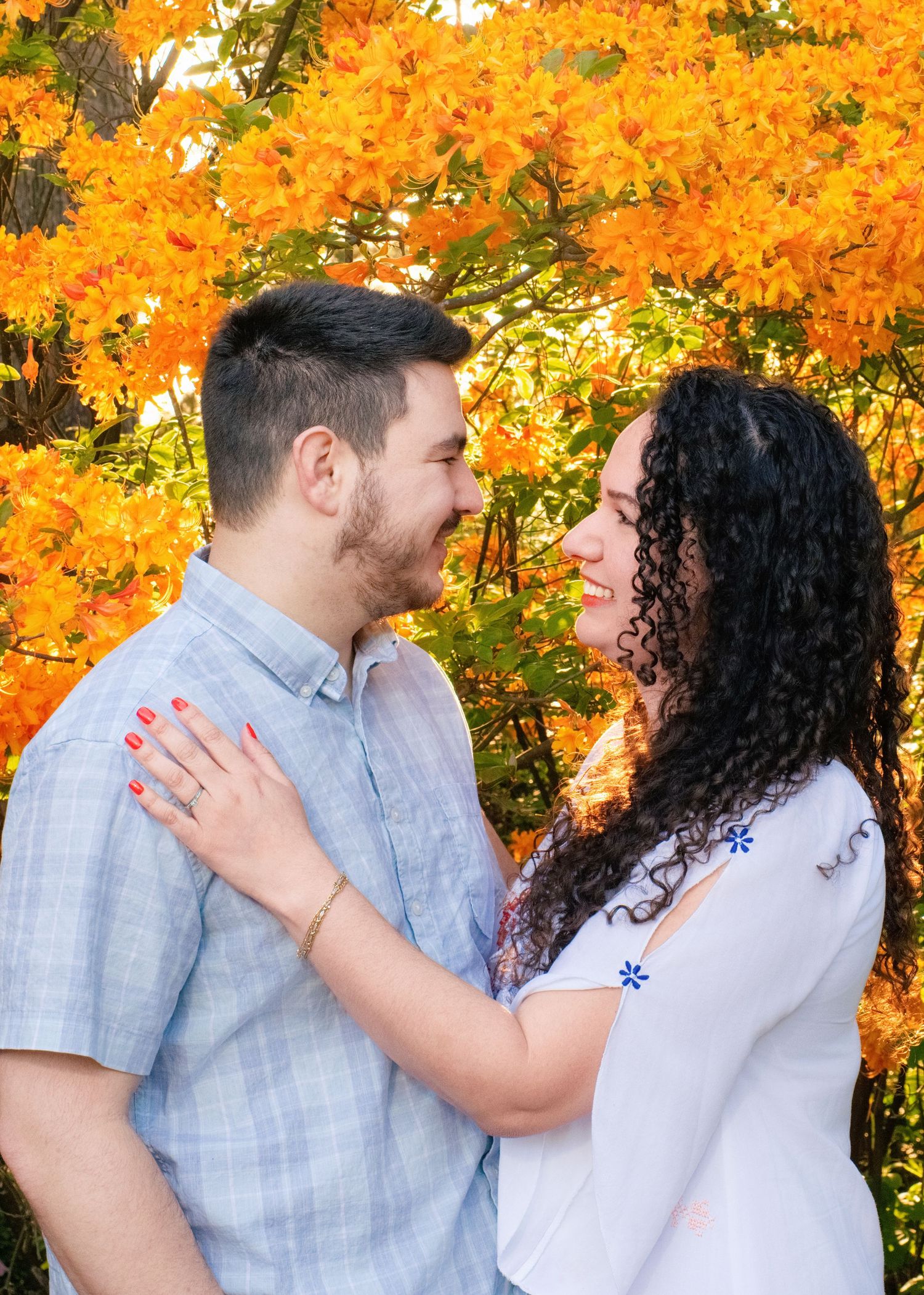 A couple shares an intimate moment sitting on wooden steps in casual fall attire.