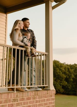 Family standing on brick porch overlooking scenic view at sunset.