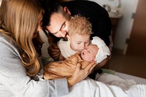A parent and child share tender moments together while relaxing on a white couch at home.