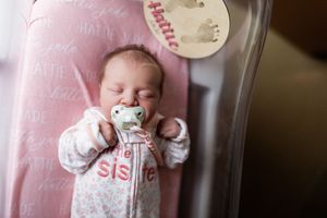 Multiple shots of a small baby in white clothing making various facial expressions against a pink background.