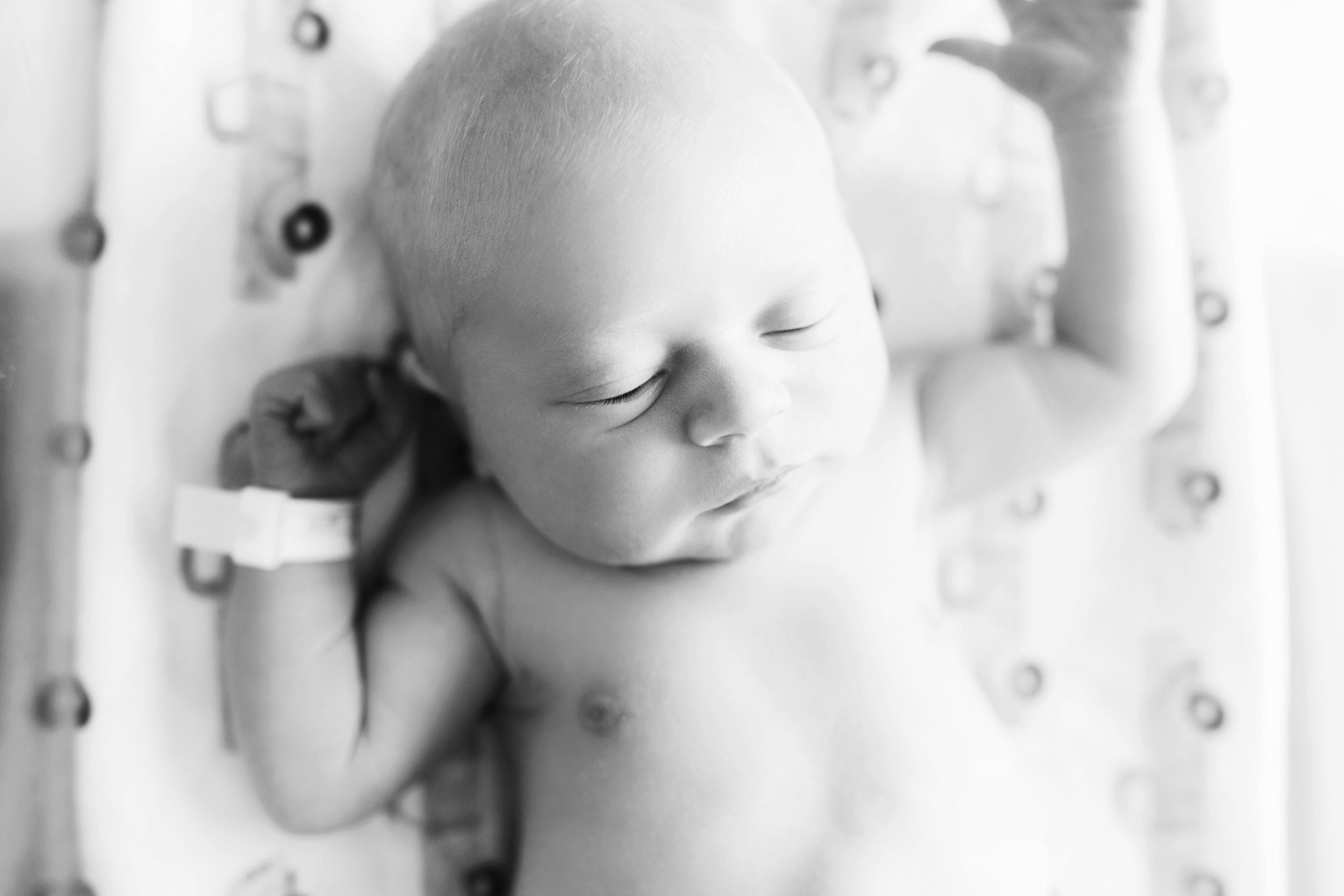 Black and white portrait of sleeping newborn on textured background.