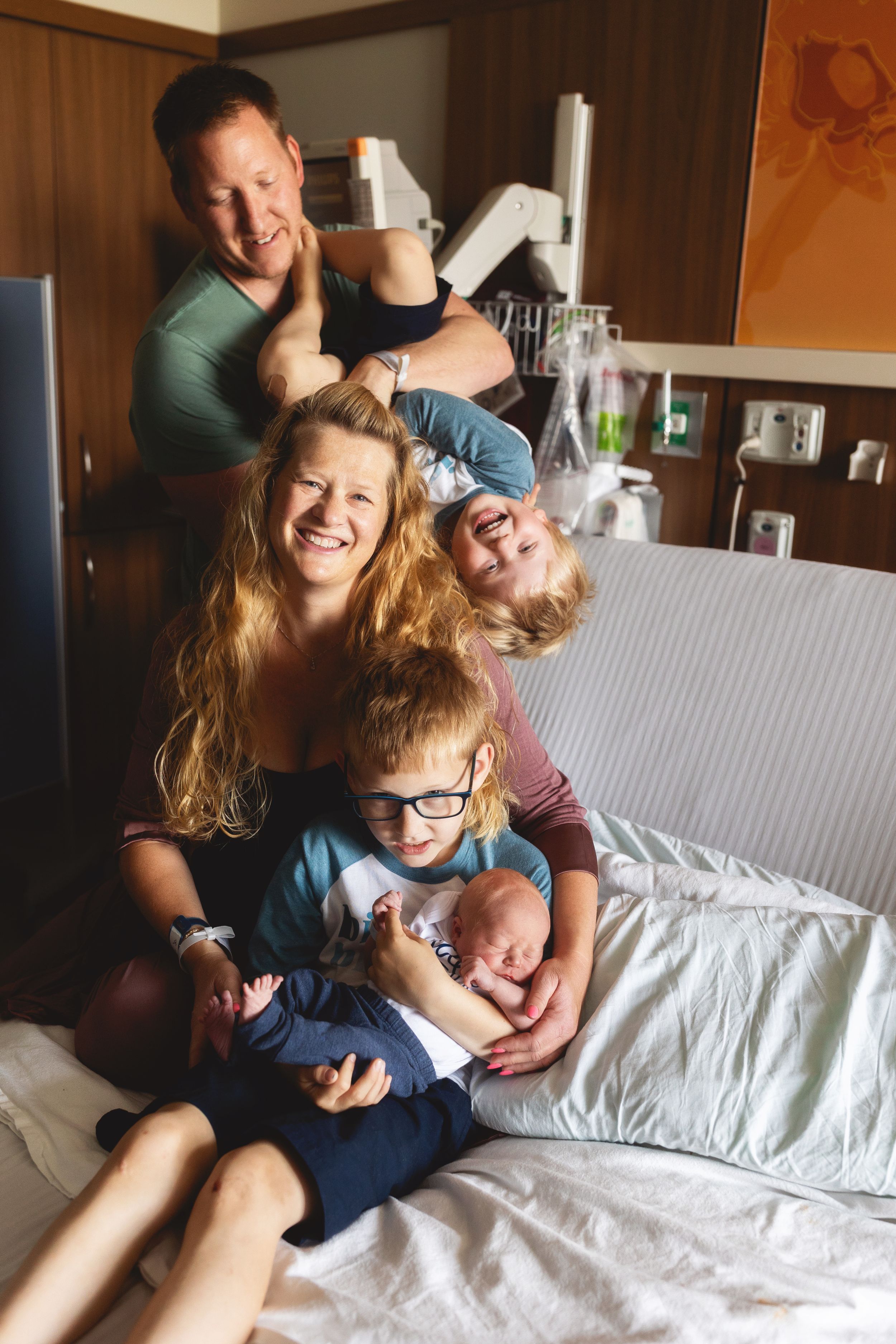 Family plays and laughs together on couch during casual home photo session.
