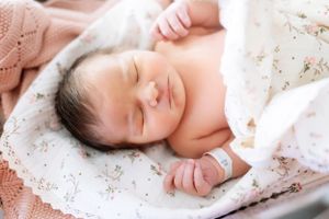 Peaceful newborn sleeping while swaddled in delicate floral and knit fabrics.