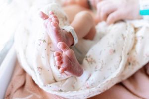 Close-up of baby feet wrapped in a delicate floral swaddle blanket.