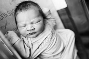 Black and white portrait of a newborn baby sleeping peacefully in a hospital bassinet.