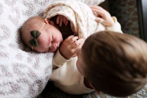 A sleeping baby wearing a bow on white lace blanket.