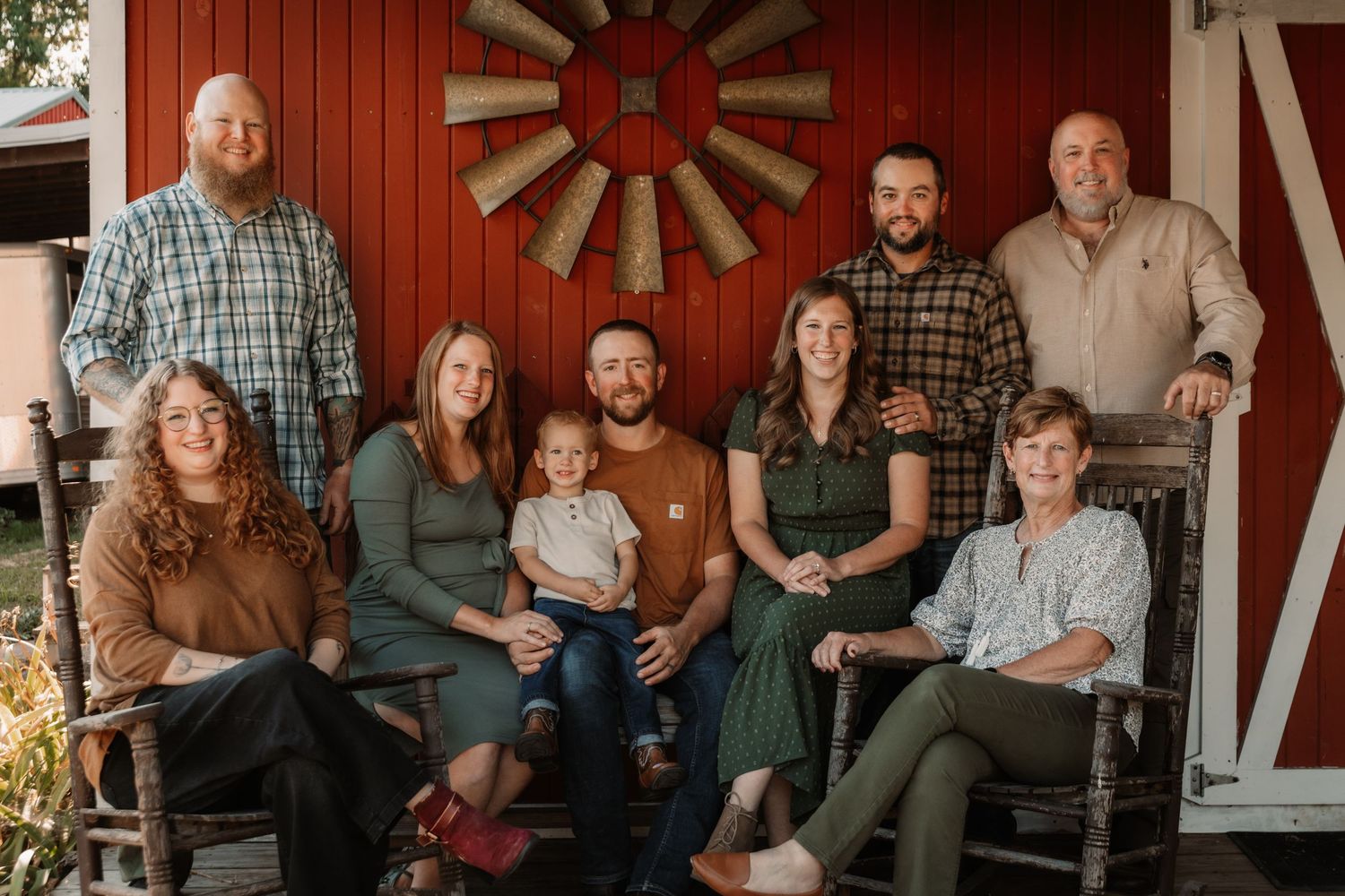 Extended family group poses together on wooded path during fall season photo session.