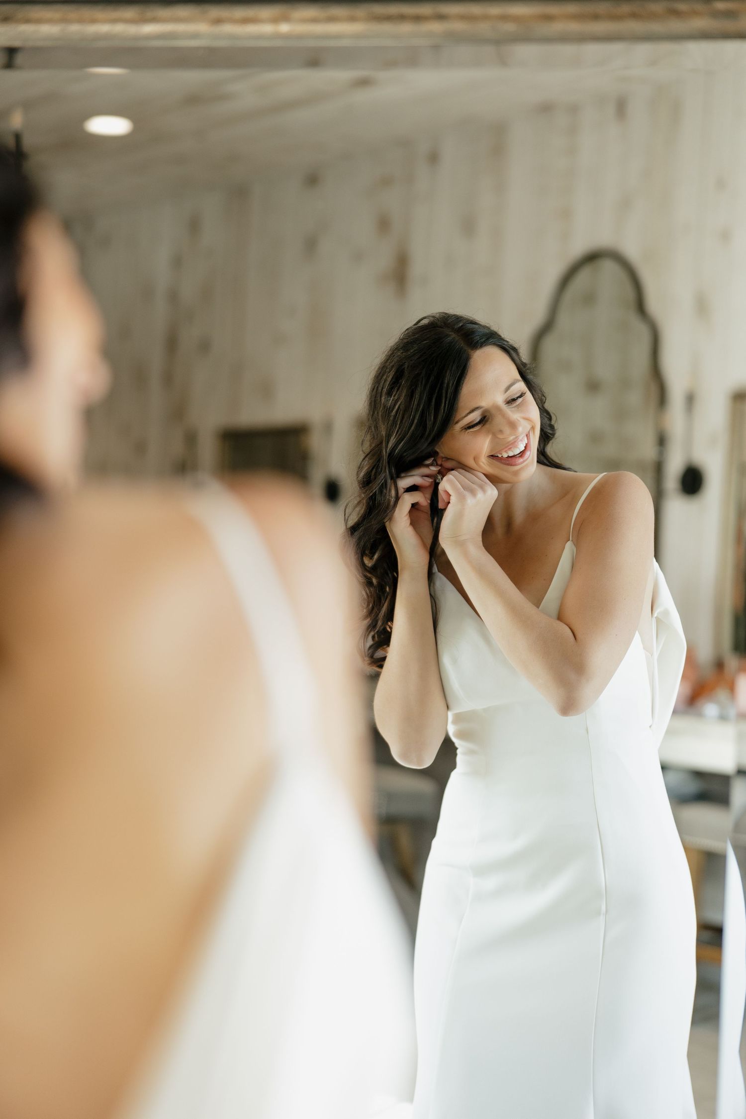 Wedding preparation scene showing someone in a white dress putting on earrings.