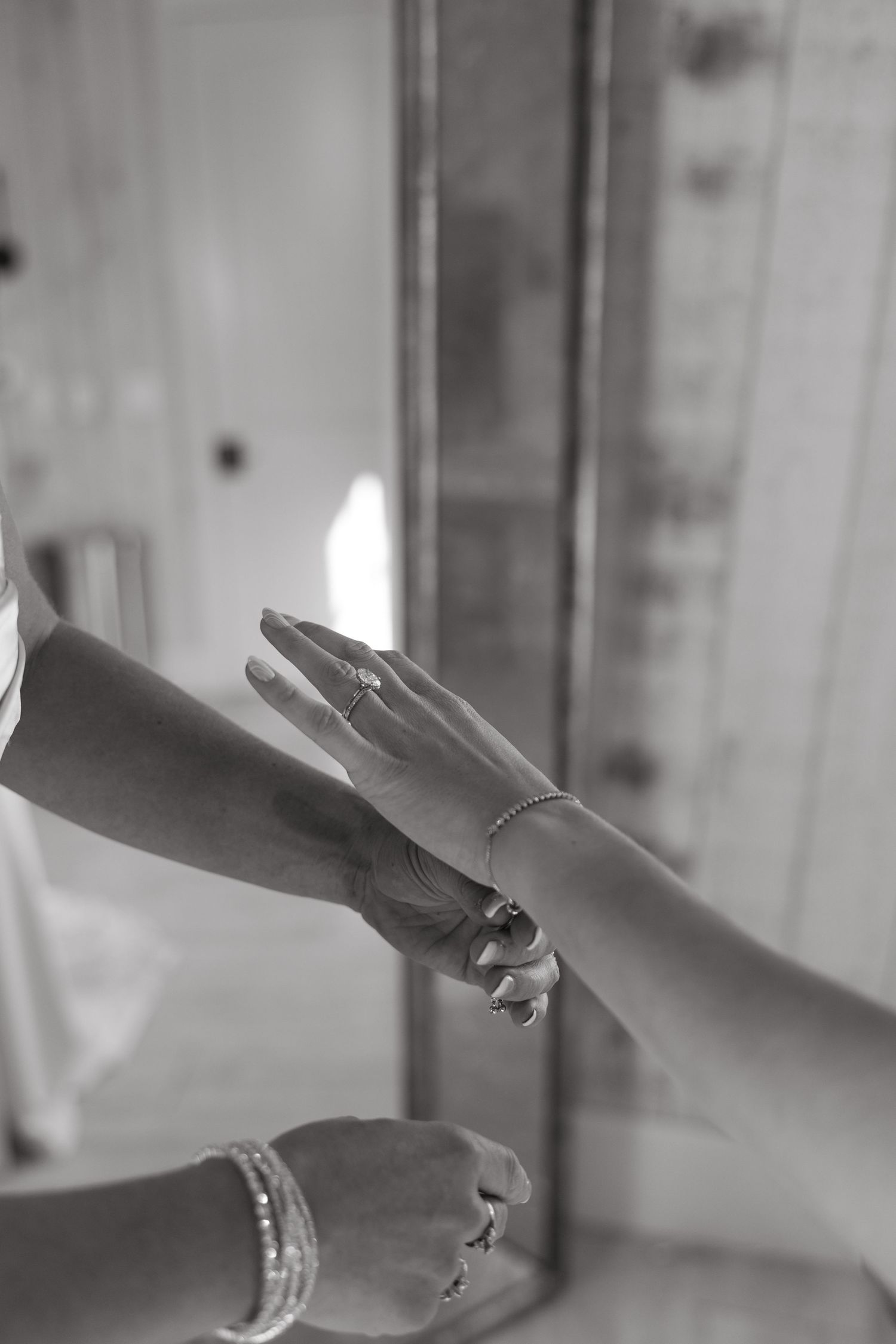 Black and white close-up of hands with jewelry during a wedding preparation.