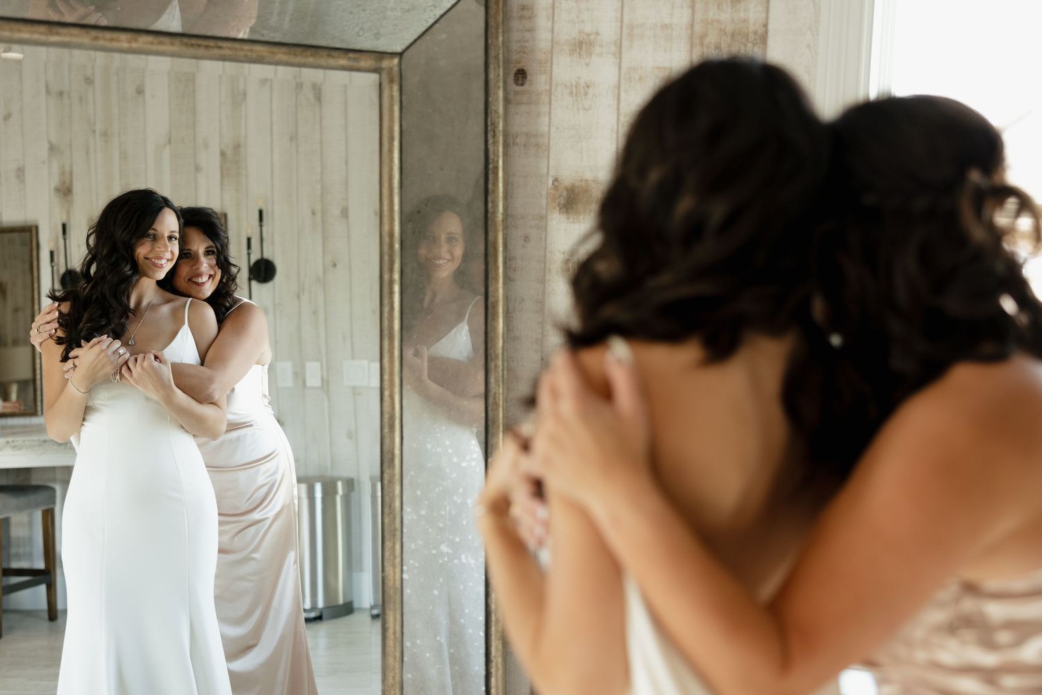 Wedding preparation scene with mirrors reflecting someone in a white dress.