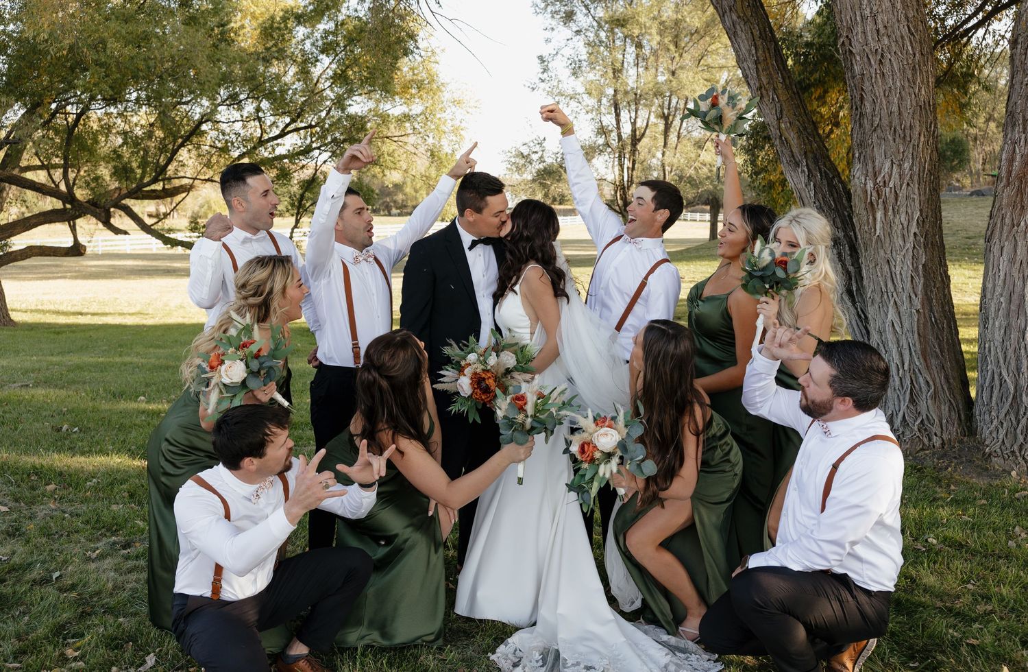 Fun candid photo of wedding party celebrating outdoors in casual poses.