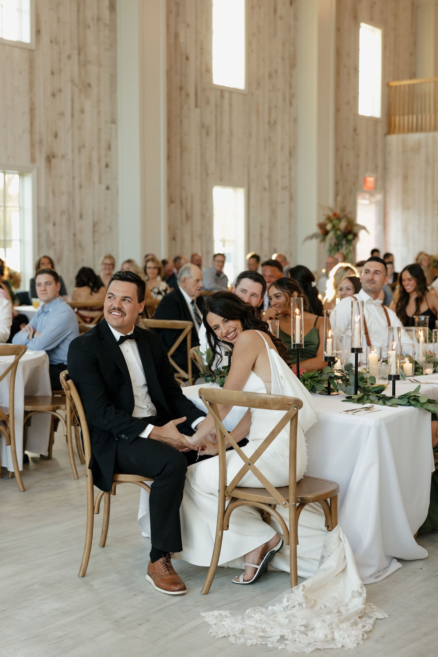 Wedding reception in a modern wooden venue with elegant table settings and natural lighting.