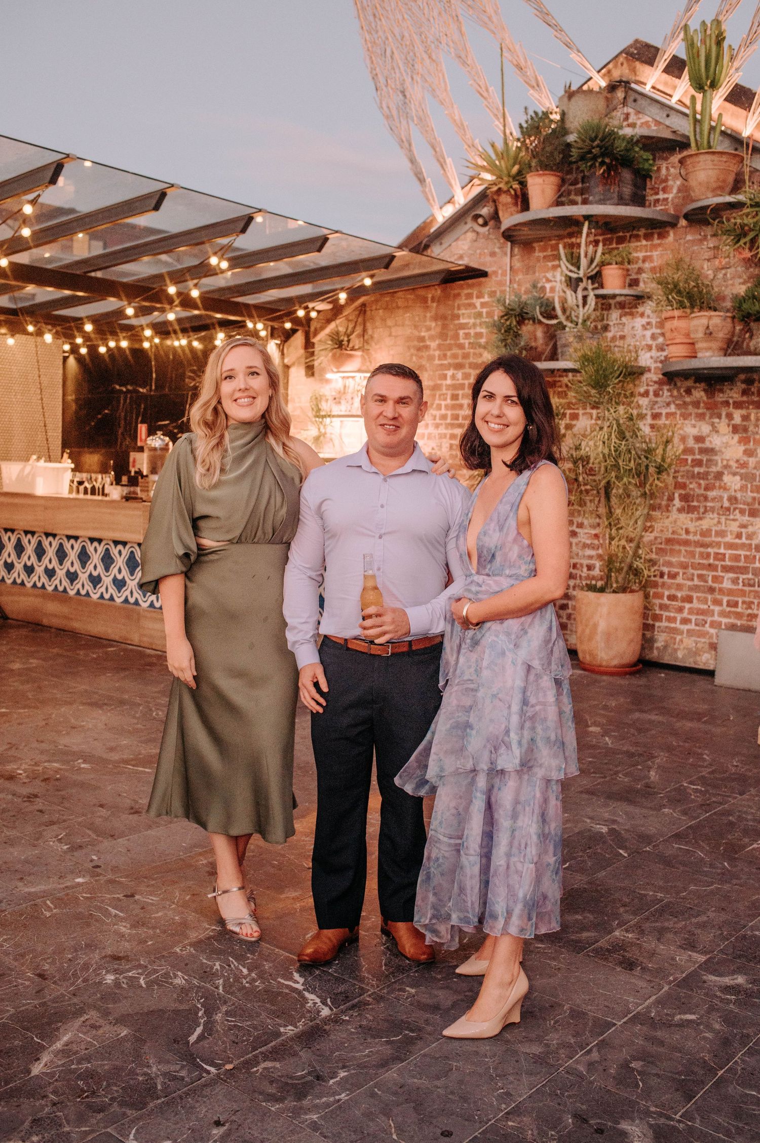 Evening rooftop gathering with string lights and exposed brick wall decor.