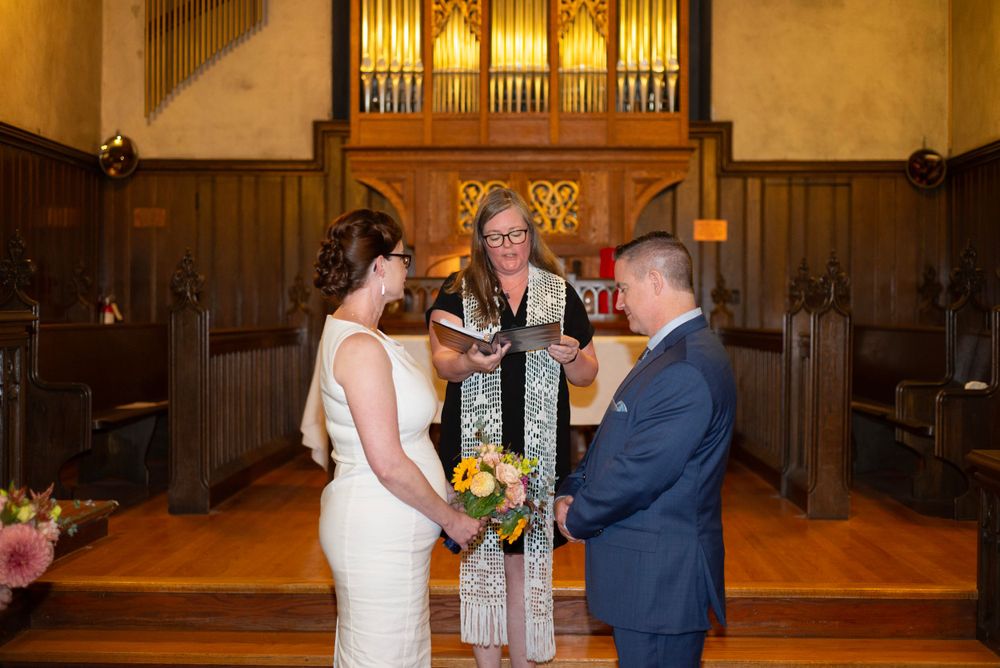 A wedding ceremony takes place in a traditional church setting with a pipe organ in the background.