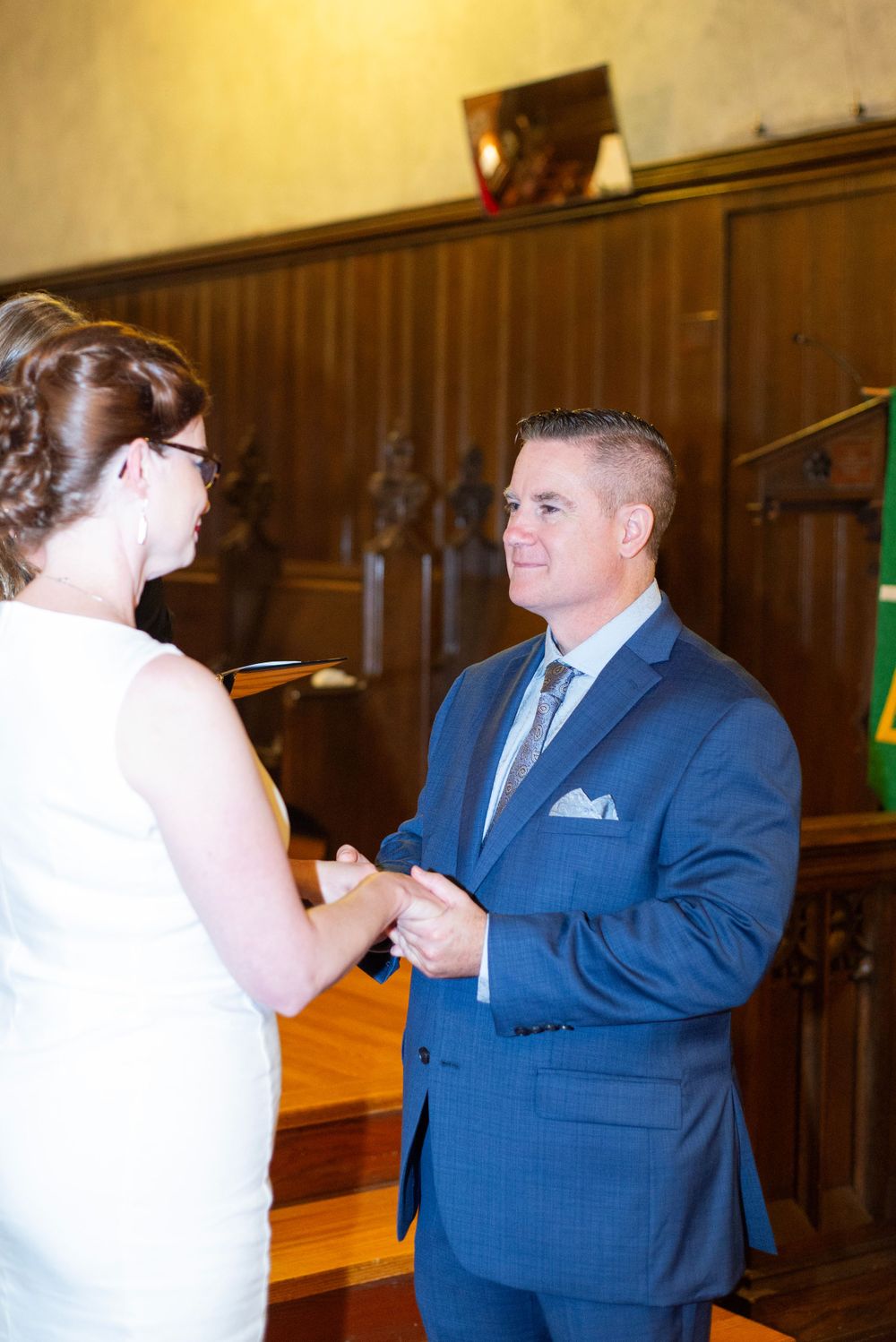 A couple exchanges rings during their wedding ceremony inside a traditional church setting.