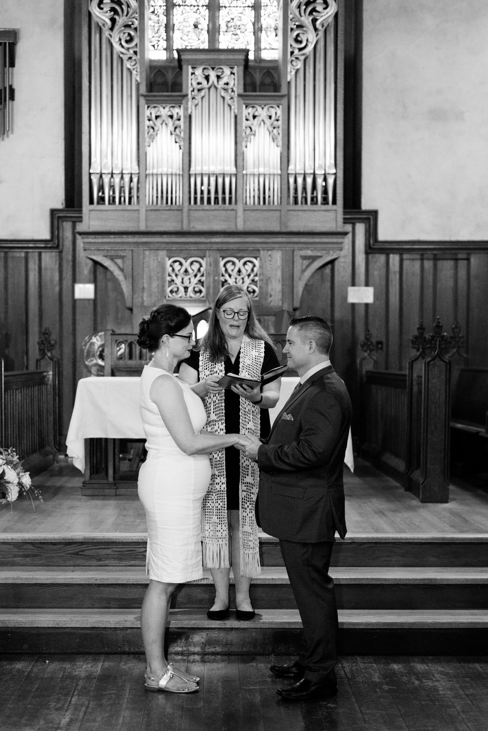Black and white photo of a traditional church wedding ceremony taking place in front of a historic pipe organ.
