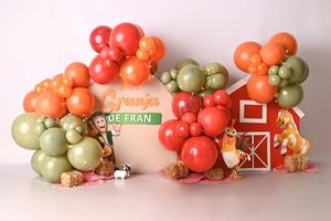 Farm-themed birthday backdrop with colorful balloon garland, barn cutout, and Granja De Fran sign with animal decorations.