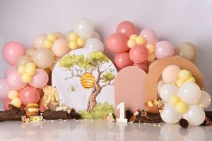 A pastel balloon garland installation with gold and white balloons decorates a beige wall in an elegant event space.