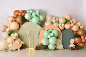Elegant balloon garland in peach and mint green colors with gold number decorations against a gray wall.