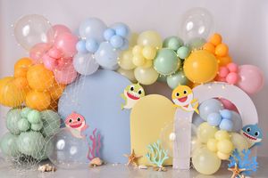 Pastel balloon arch with smiling cloud decorations and a yellow door backdrop for a whimsical party setup.