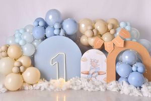Pastel blue and beige balloon garland with number one candle creates an elegant first birthday party decoration display.