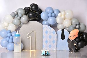 A modern baby shower decoration setup with blue and white balloon garlands, number one sign, and black accent balloons.