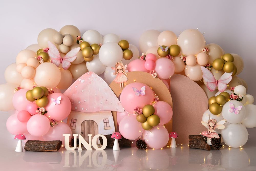 Pink and gold balloon garland with floral decorations creates an elegant backdrop for special occasions.
