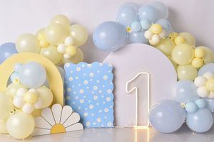 Blue and yellow balloon arch with daisy decor and number one candle for first birthday party celebration setup.