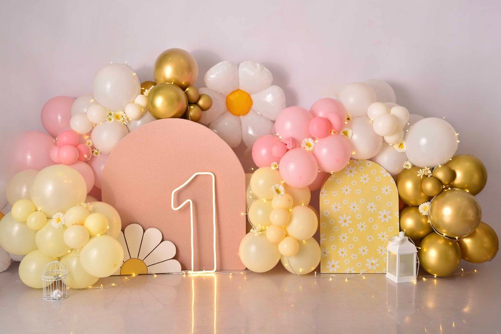 Elegant balloon garland with pink, gold, and white balloons decorates a beige wall with illuminated number one decor.