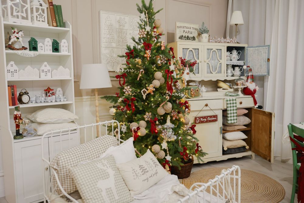 Cozy white room with Christmas tree, built-in shelving, and white metal daybed with pillows.
