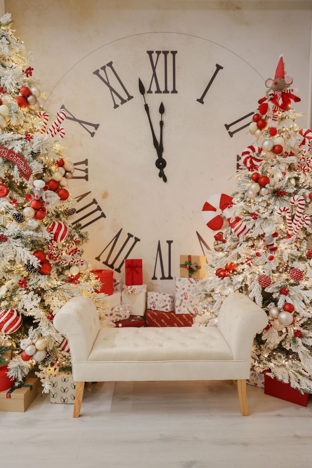 Large wall clock flanked by two flocked Christmas trees with red and white peppermint decorations.