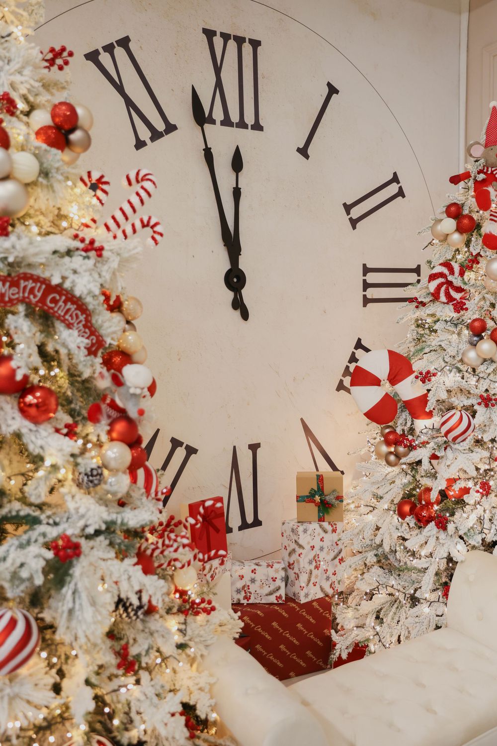 Large wall clock surrounded by flocked Christmas trees with red and white peppermint decorations.