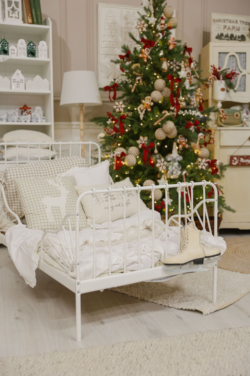 White metal bed frame with cozy bedding next to decorated Christmas tree in rustic room setting.