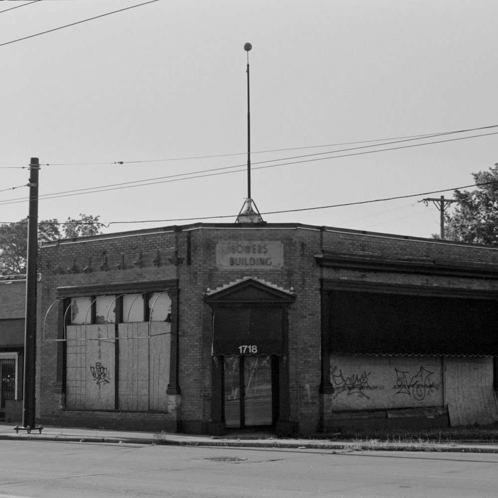 Abandoned brick commercial building with boarded up windows and an Art Deco facade on a city corner.