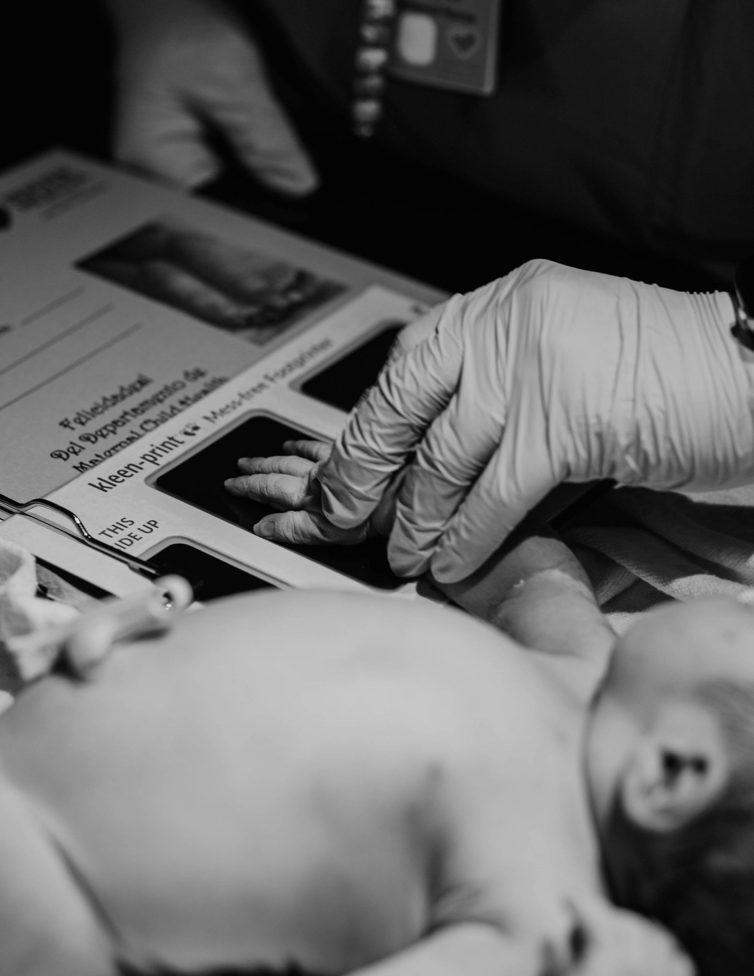 A medical professional in latex gloves examines a patient on an examination table in black and white.