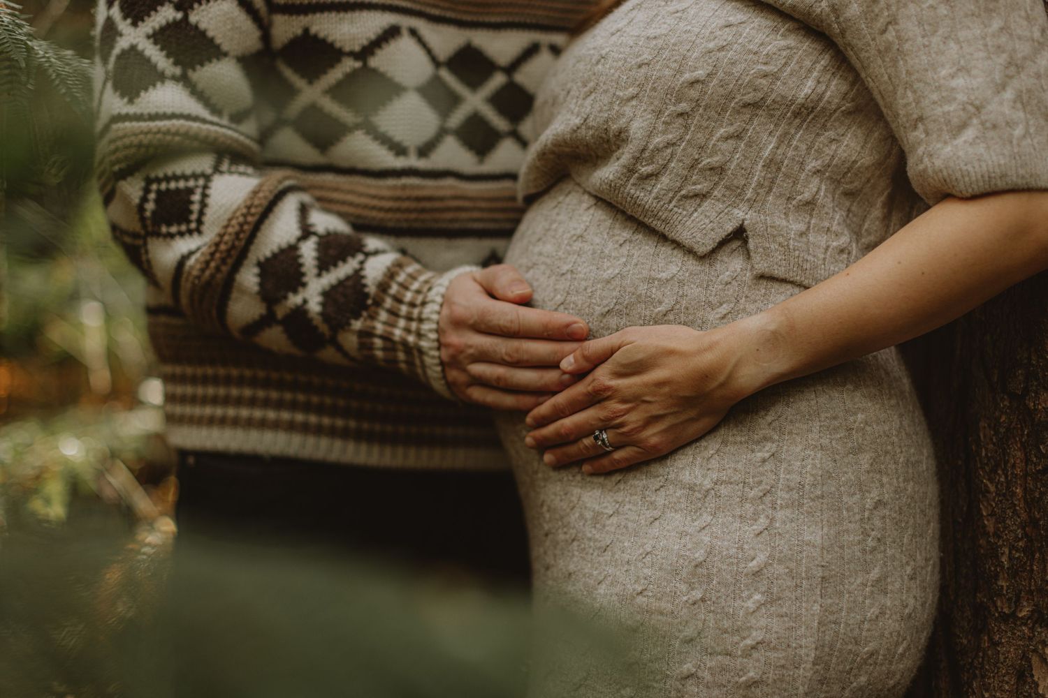 Side view of pregnant woman in white sweater during outdoor maternity photoshoot.