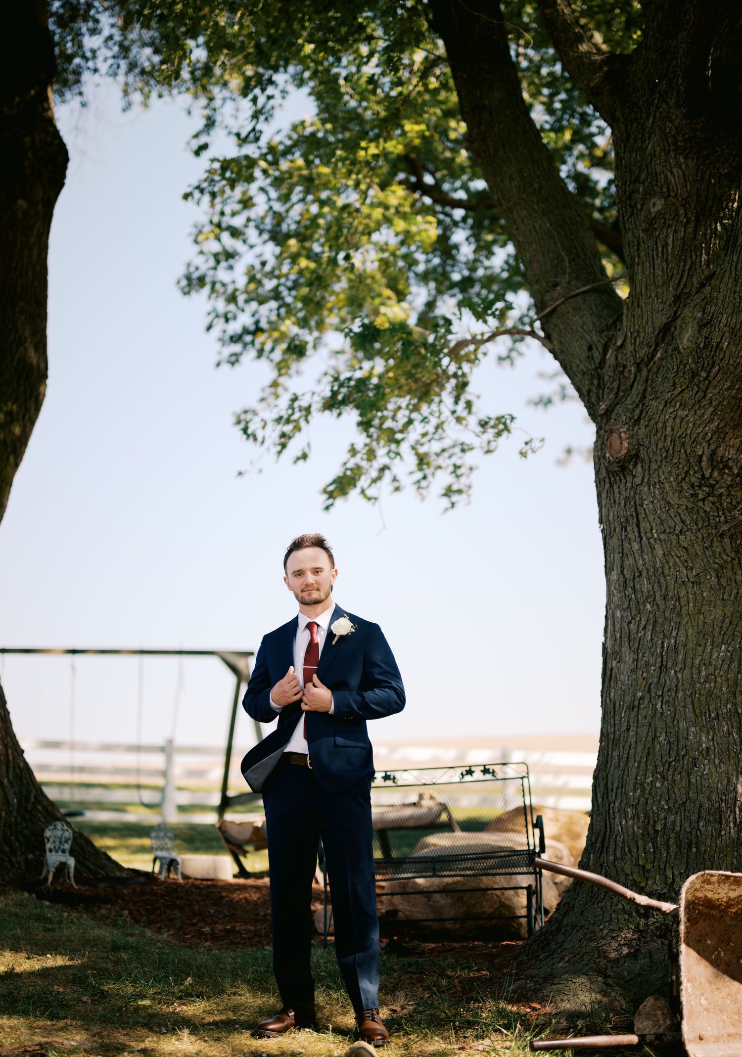 A formal portrait under a large tree with rolling hills in the background.