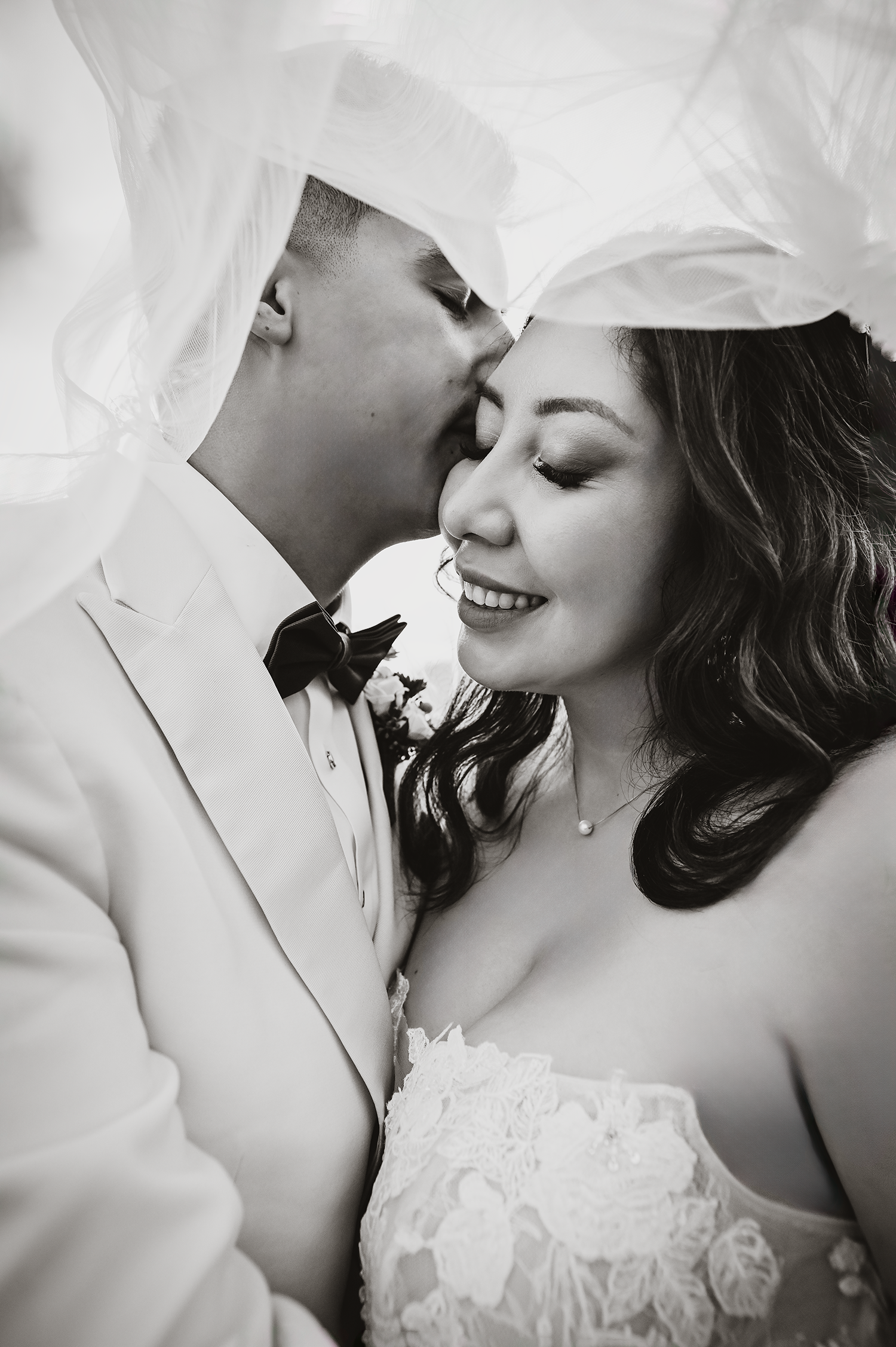 An intimate black and white wedding portrait showcasing a tender moment between newlyweds.